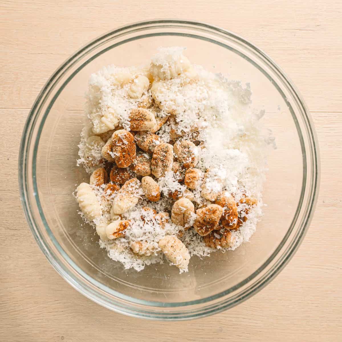 Seasoning gnocchi with parmesan, dried basil, garlic, oil, and paprika for air fryer gnocchi.
