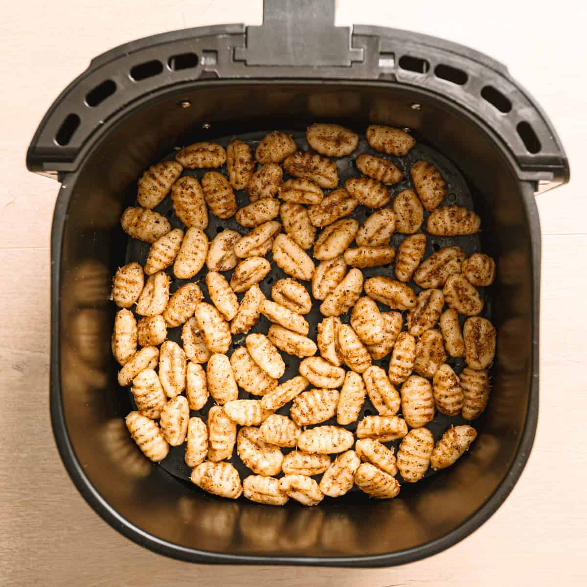 Gnocchi arranged in a single layer in an air fryer basket for air fryer gnocchi.