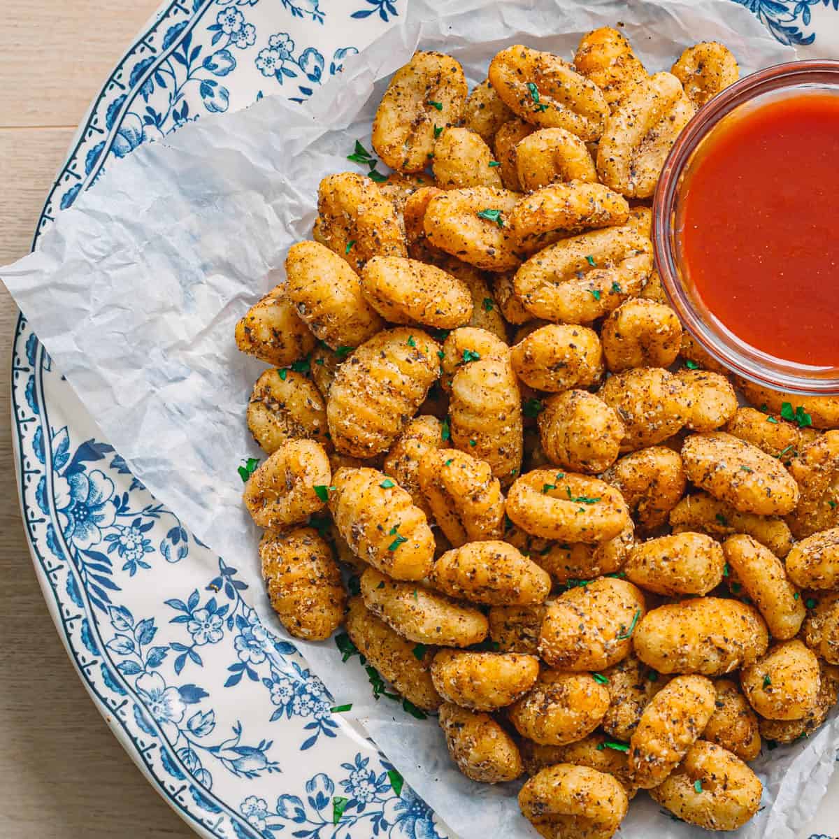 Air fryer gnocchi with marinara sauce on the side in a ceramic bowl.