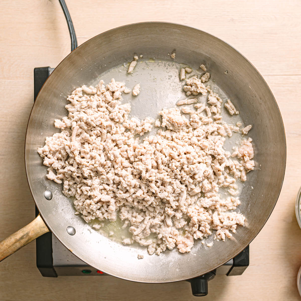 Ground chicken cooking in a pan for easy ground chicken stir fry, broken into small pieces as it browns.