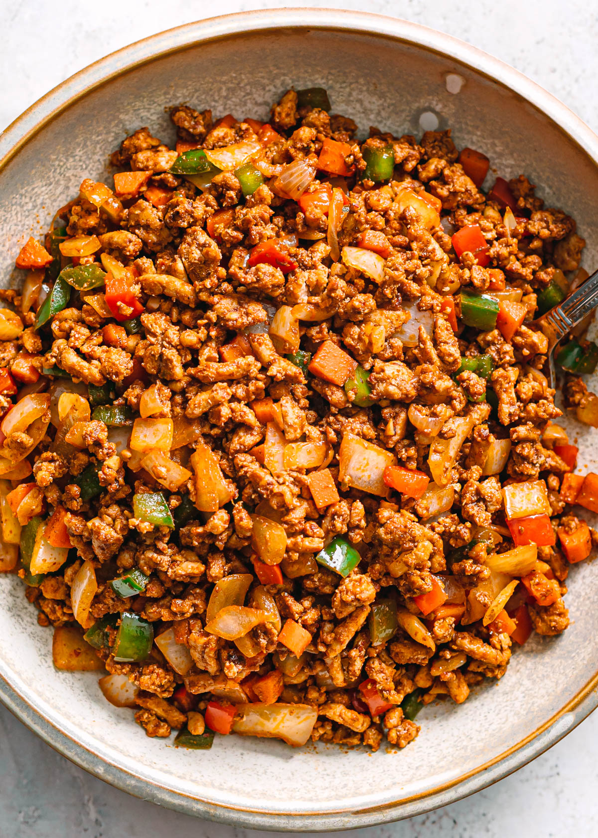 Easy ground chicken stir fry with colorful vegetables in a ceramic bowl.