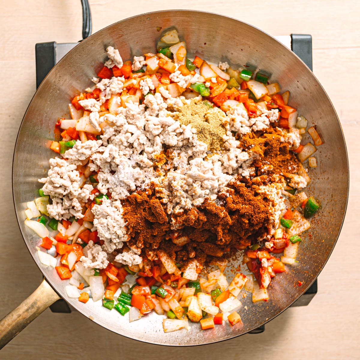 Ground chicken stir fry with tomato paste and Tex-Mex spices being mixed in a pan.