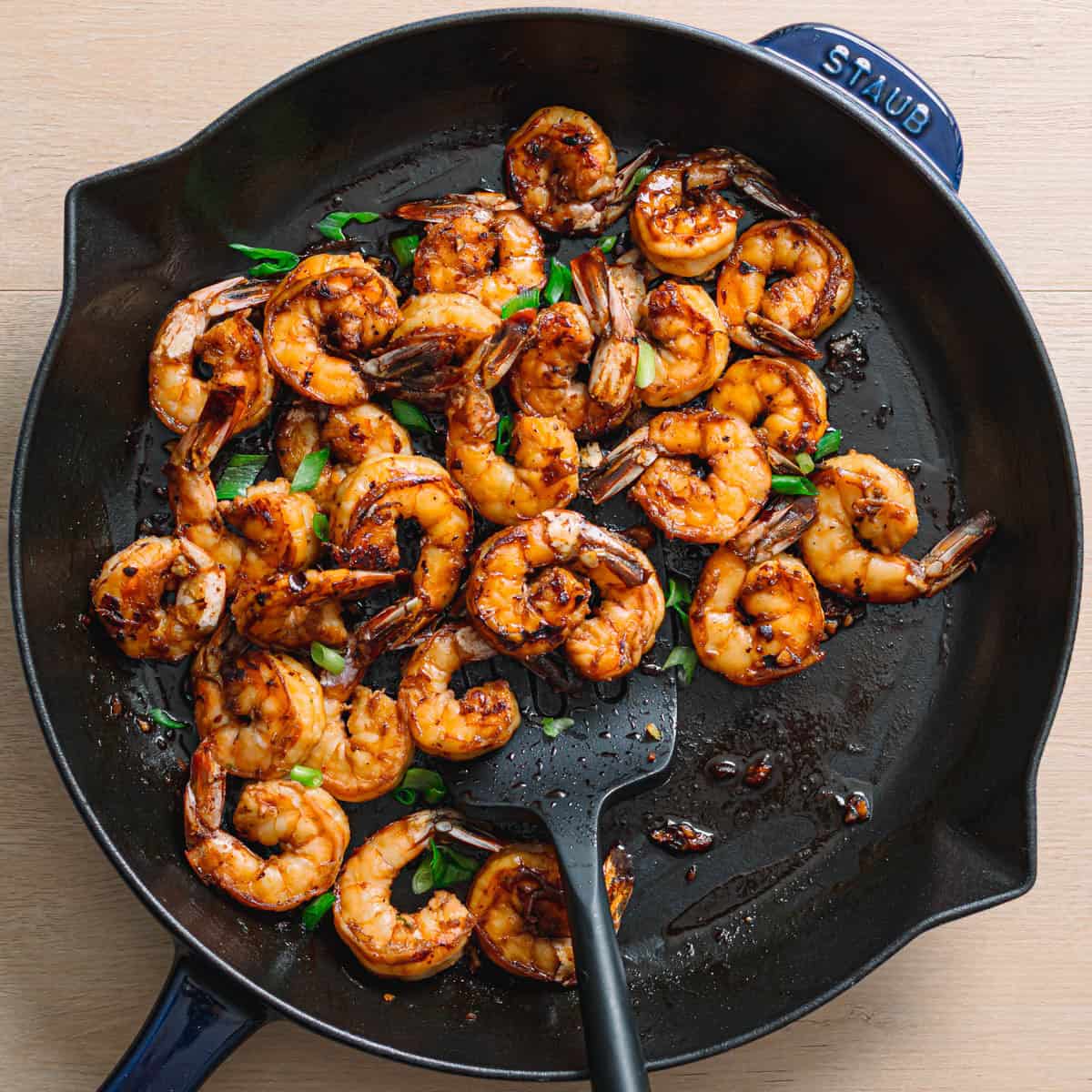 Shrimp coated in honey garlic sauce in pan for sweet savory shrimp recipe cooking process.