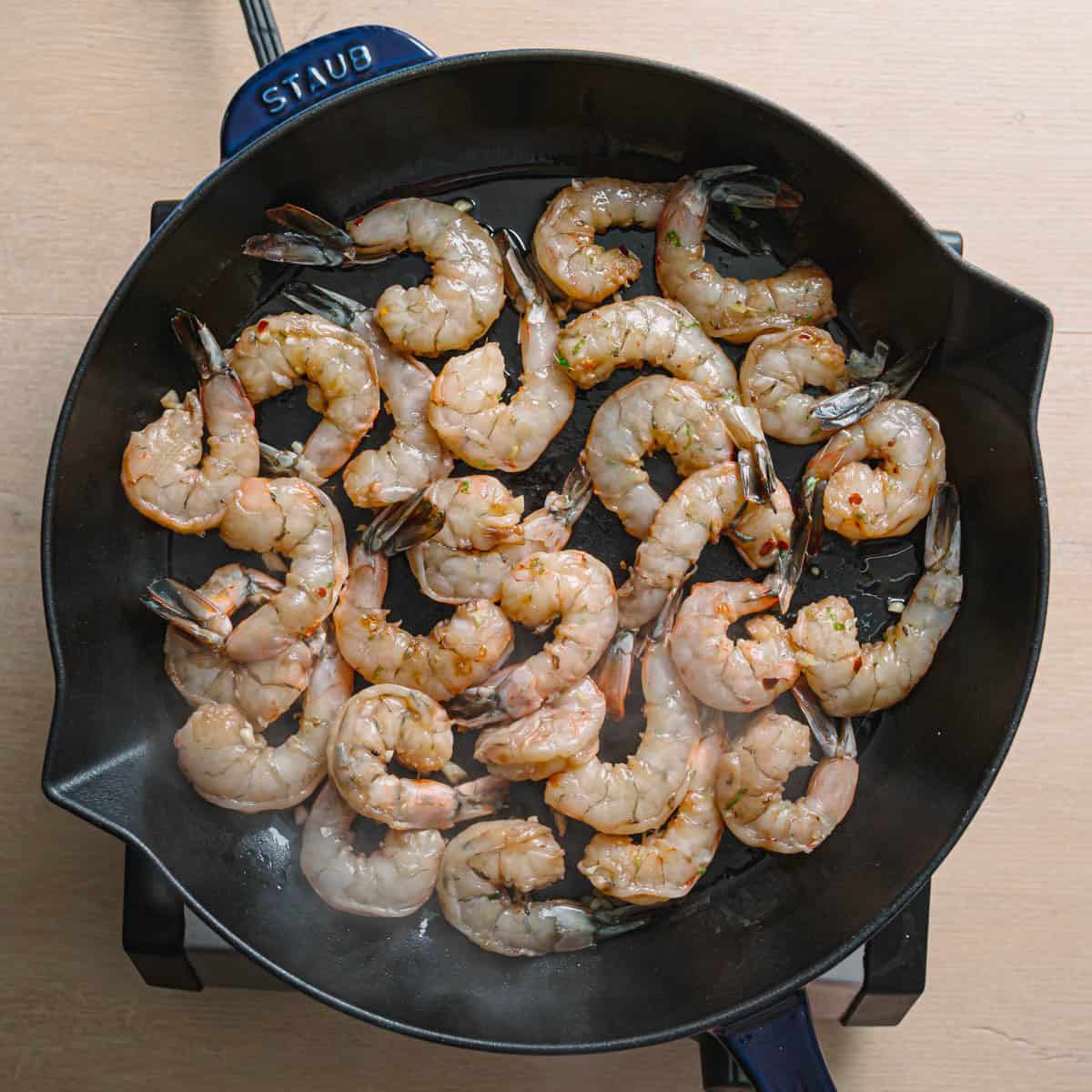 Cooking honey garlic shrimp in skillet with sizzling sauce for quick easy seafood dinner.