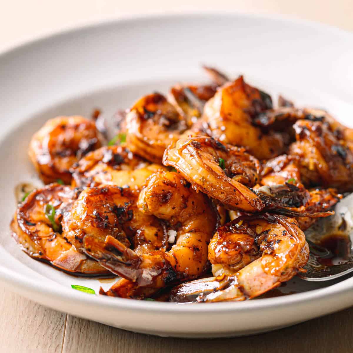 Sweet and savory honey garlic shrimp plated in ceramic bowl with sauce glaze.