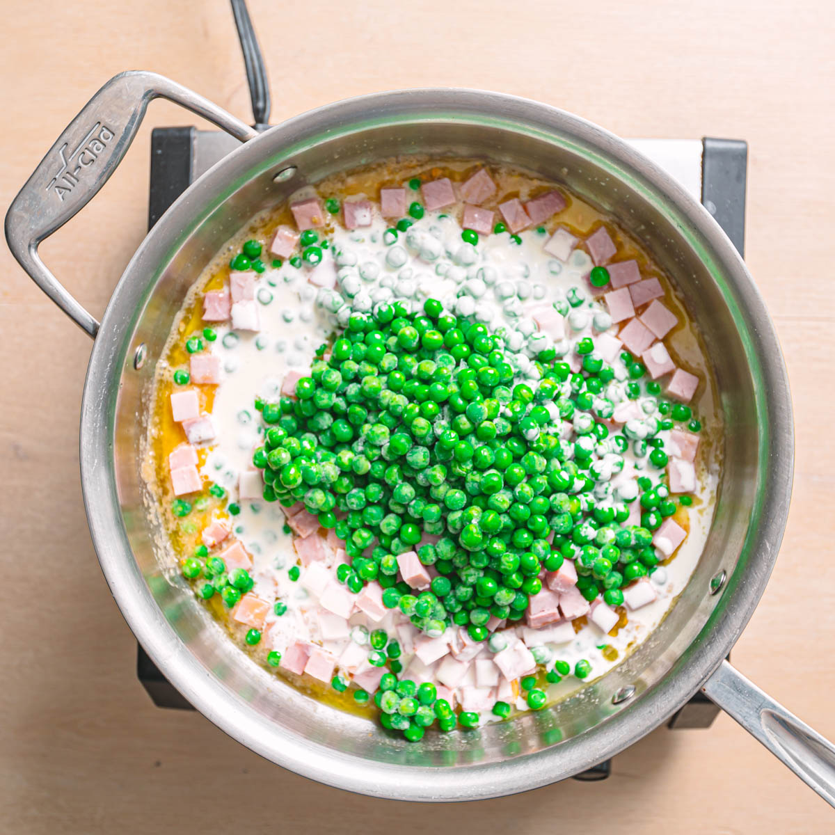Garlic parmesan cream sauce being prepared in a skillet with pasta being added.