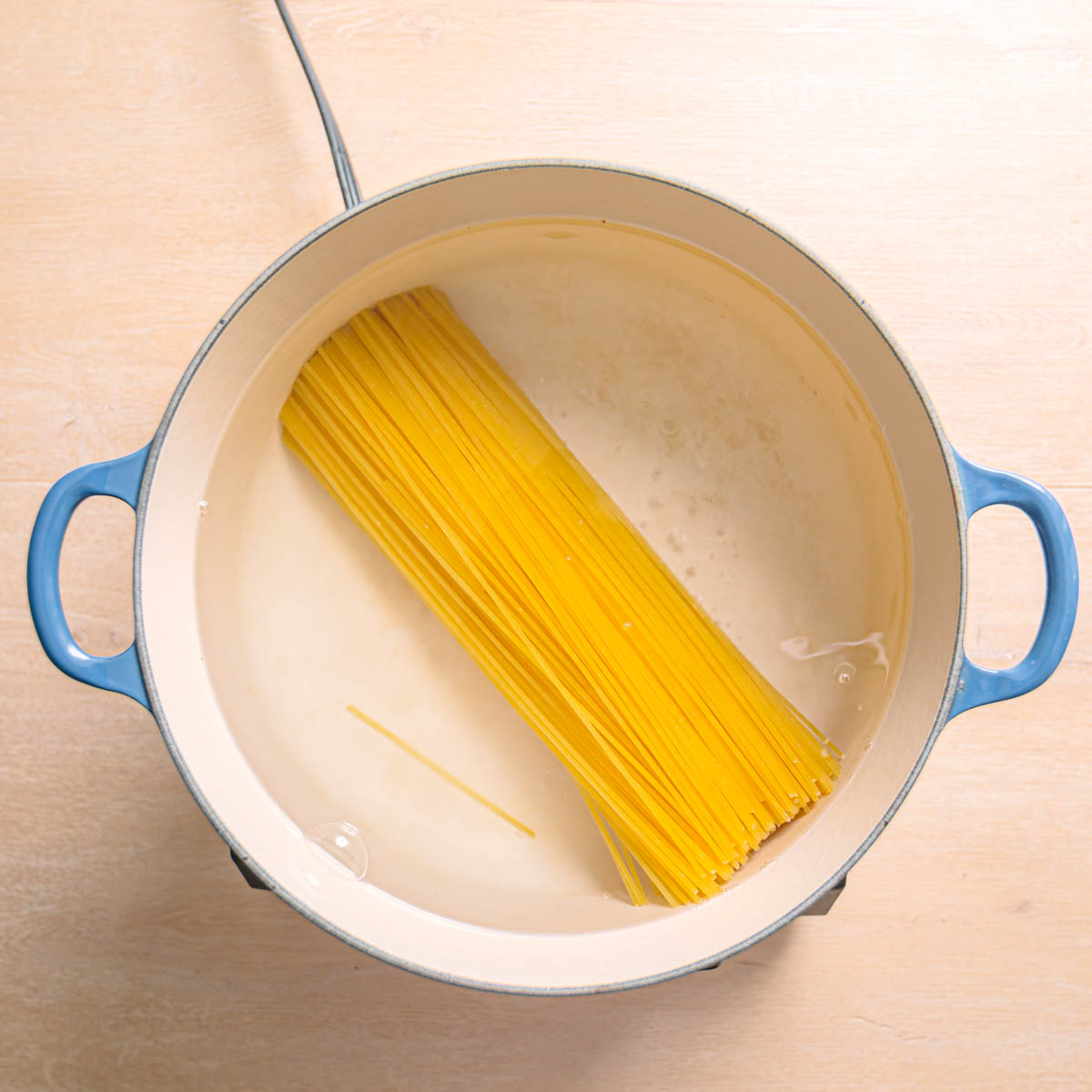 Spaghetti cooking in a pot of boiling water on a stovetop.