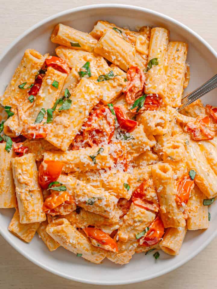 creamy Boursin tomato pasta with rigatoni served in ceramic bowl topped with basil and Parmesan.