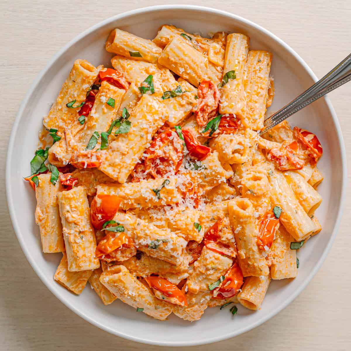 creamy Boursin tomato pasta with rigatoni served in ceramic bowl topped with basil and Parmesan.