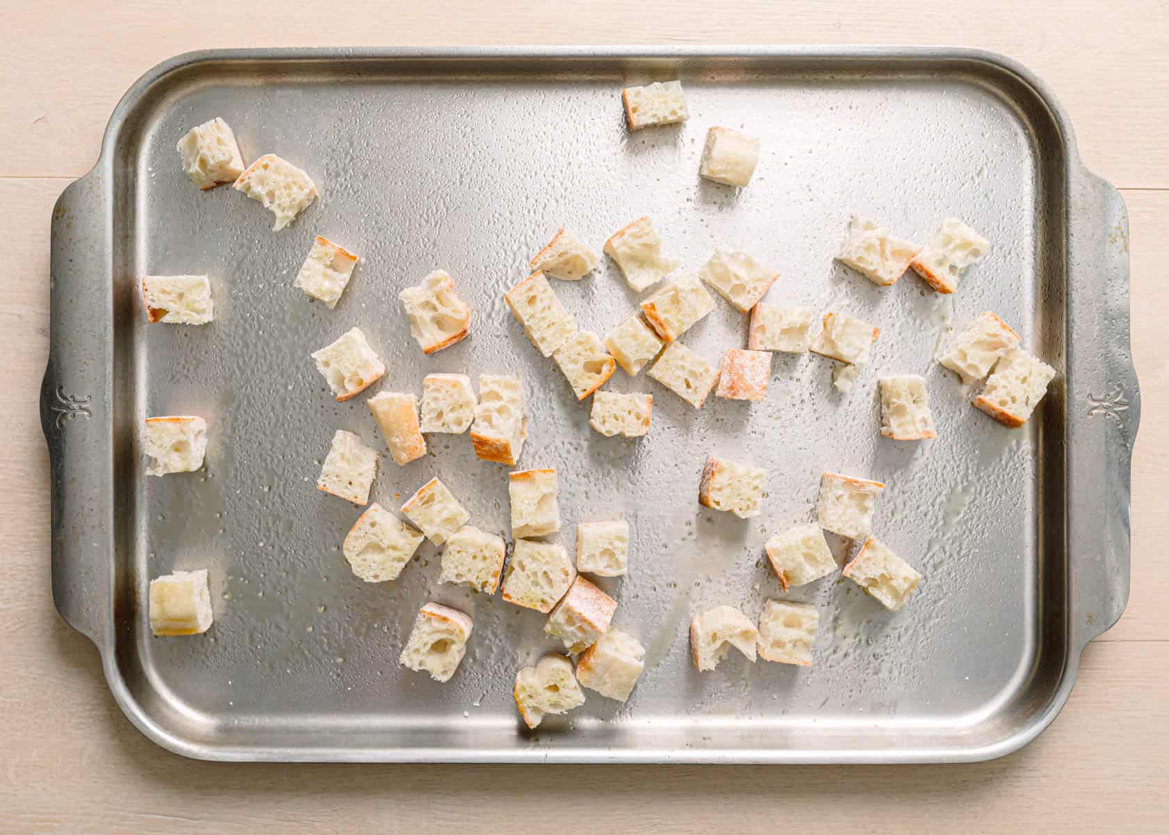 Easy panzanella salad recipe toasted ciabatta bread cubes on a baking sheet golden and crispy.