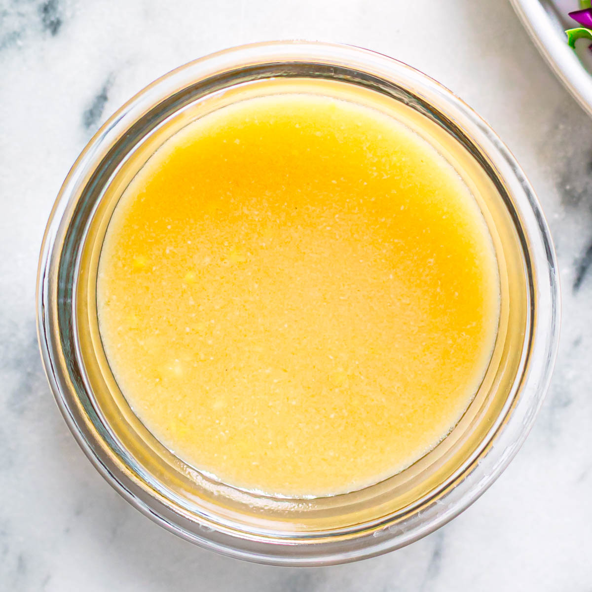 Homemade miso ginger dressing overhead view in a glass jar showing smooth golden texture.