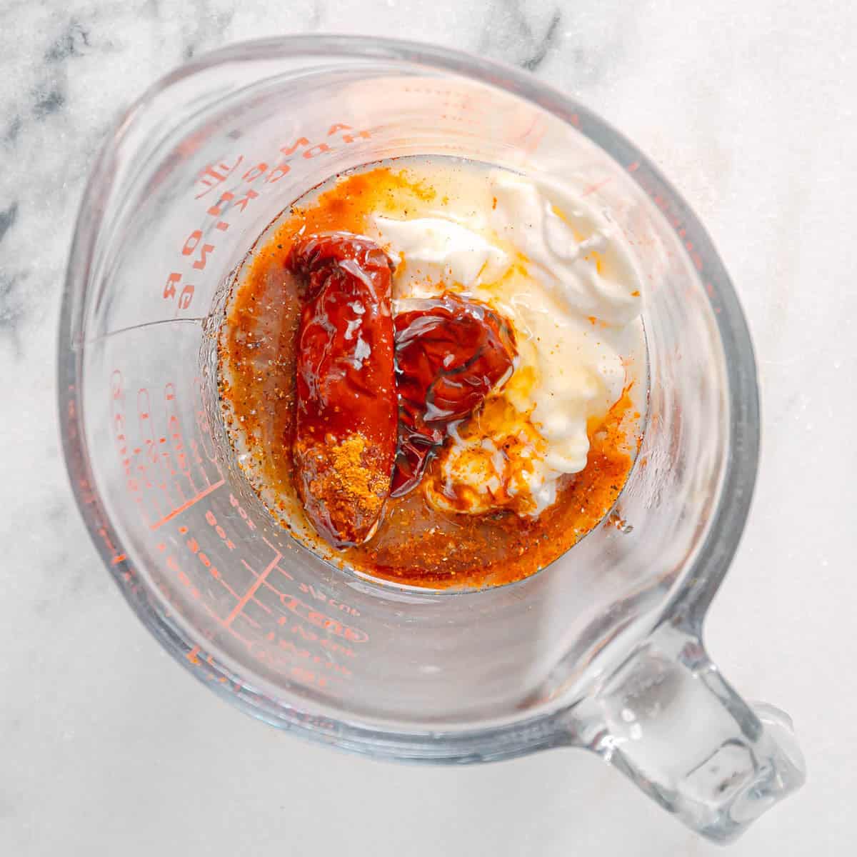 Adding mayo, sour cream, and chipotle peppers to a mixing bowl for creamy chipotle sauce.
