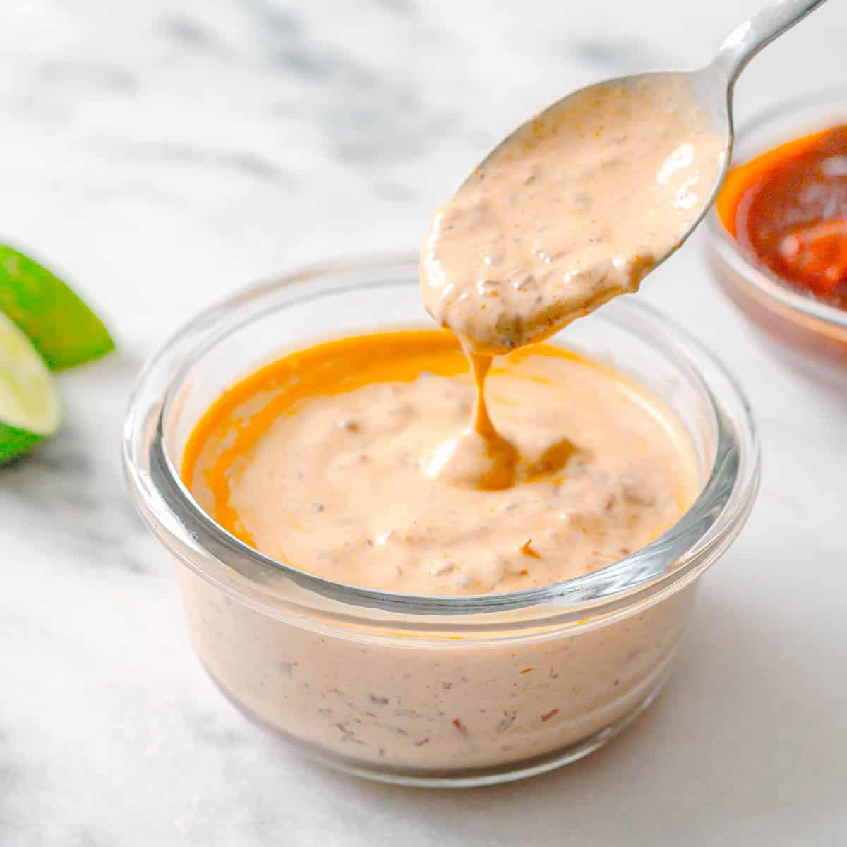 Side view of creamy chipotle sauce in a bowl with a spoon.