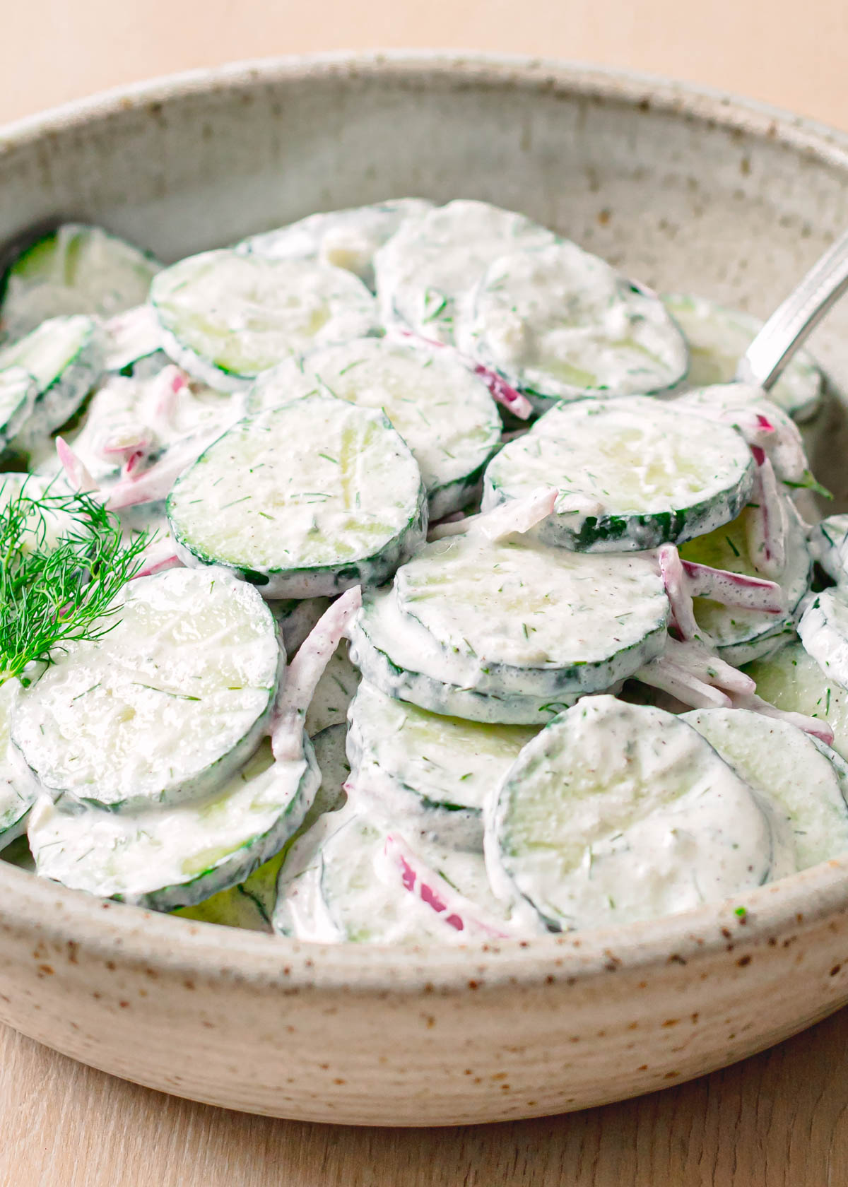 Side view of creamy cucumber dill salad in a bowl.