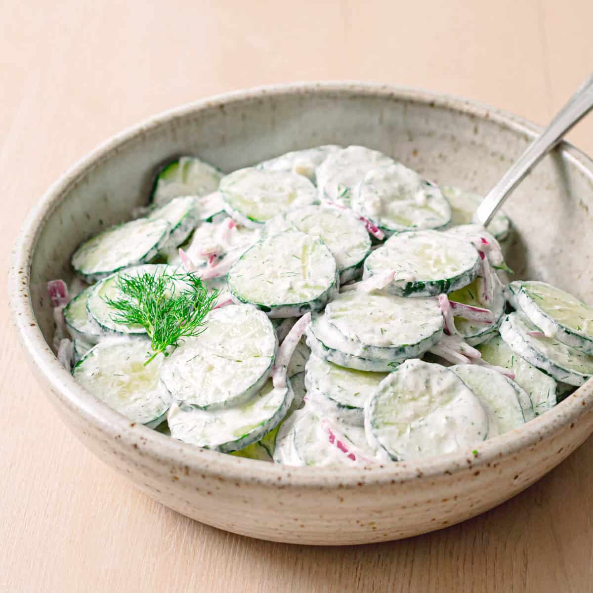 Close side view of cucumber dill salad with dill on top.