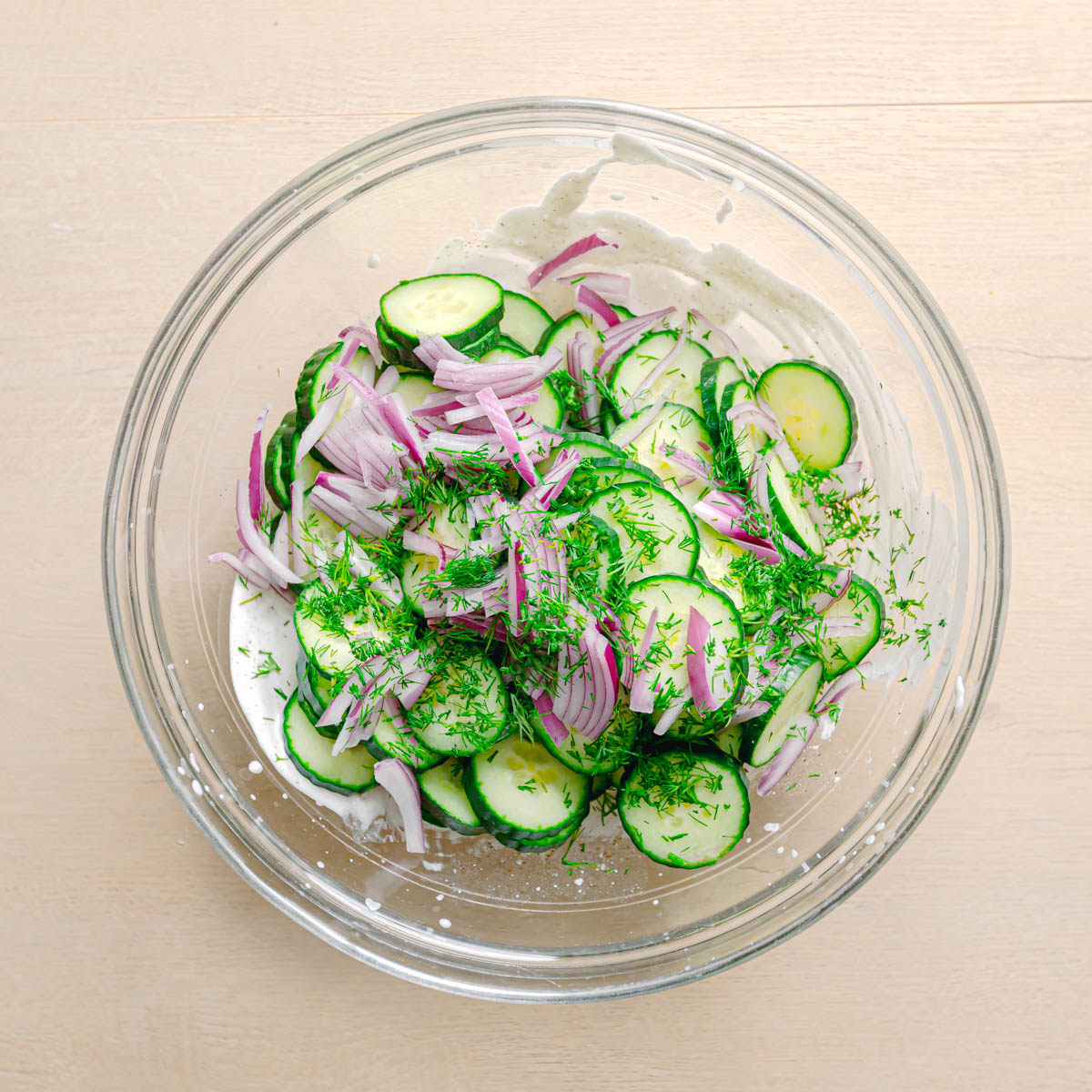 Adding sliced cucumber and fresh dill to the dressing.