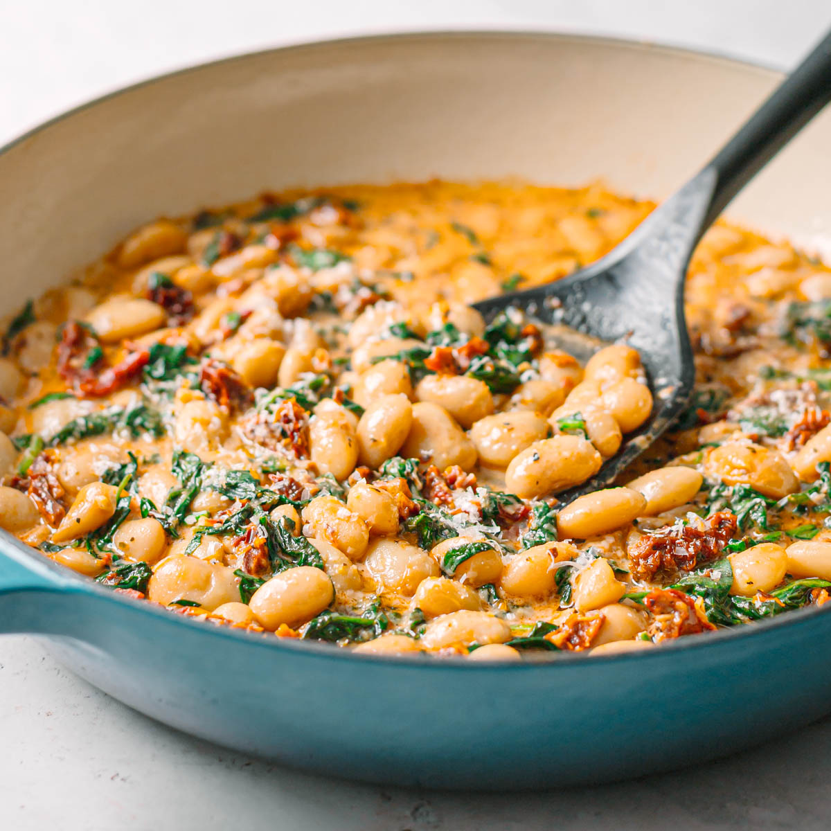 Side view of creamy marry me butter beans in a Le Creuset casserole dish, showing the thick tomato cream sauce.