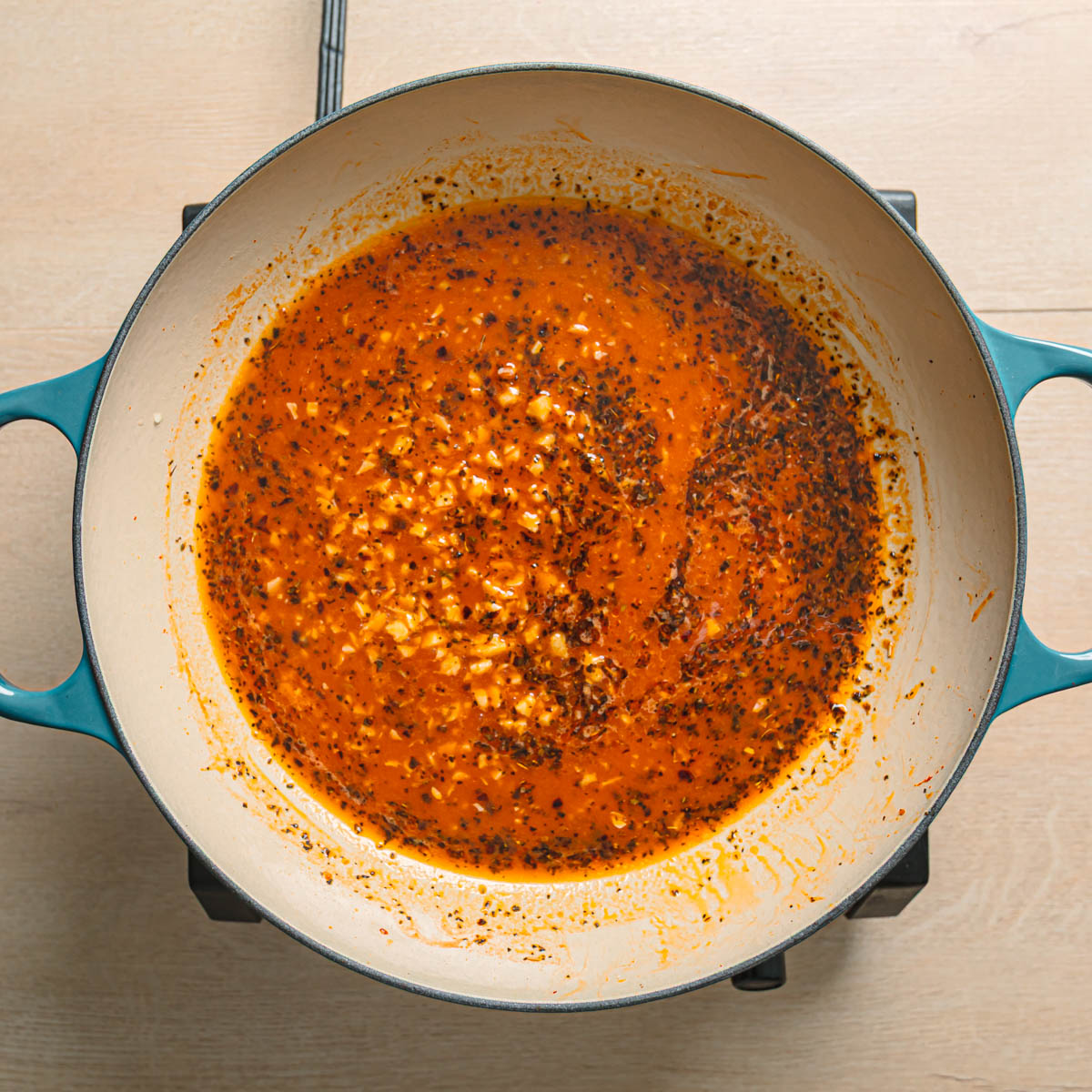 Chicken broth simmering in a pan to build the base of marry me butter beans sauce.