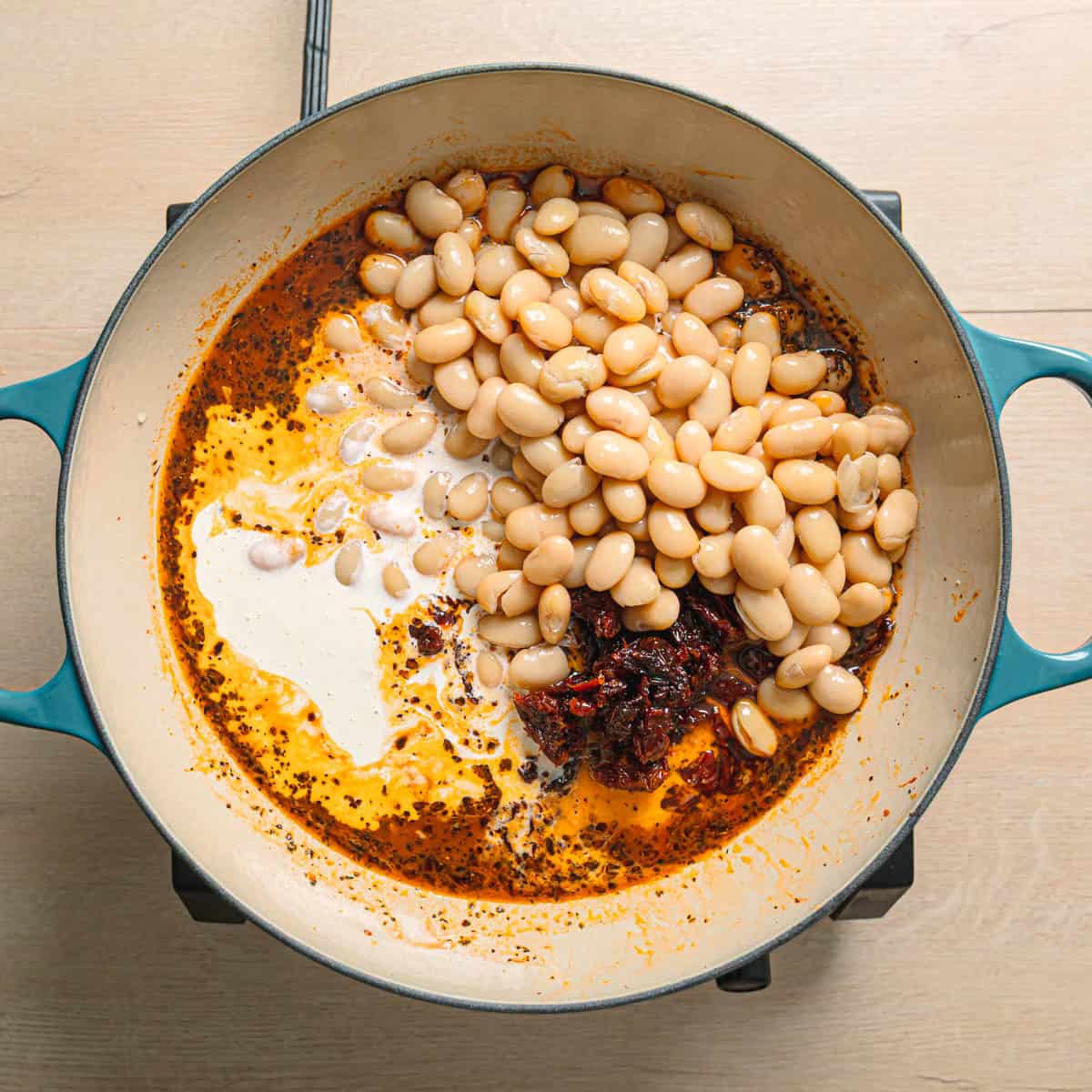 heavy cream, milk, sun dried tomatoes, and butter beans added to the simmering sauce.