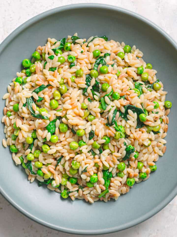 Bowl of orzo with peas and spinach, top view.